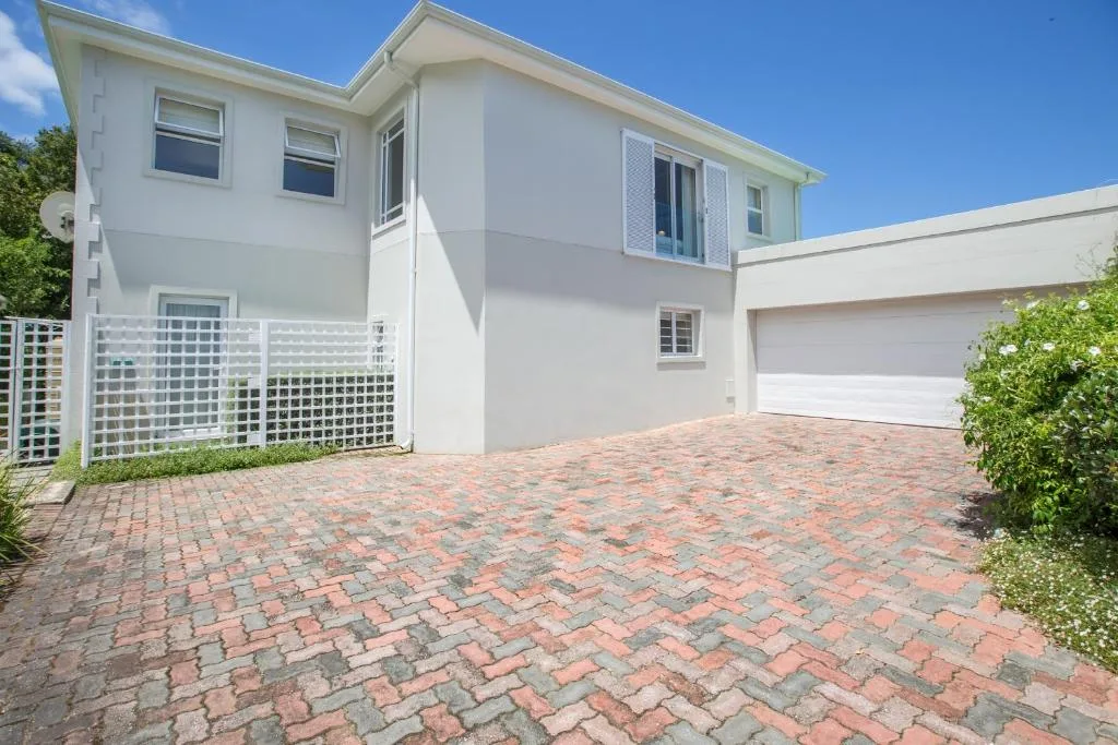Modern white two-story house with brick driveway and garage entrance