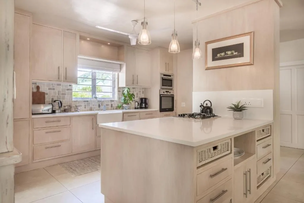 Modern cream kitchen with island, pendant lights, and builtin appliances