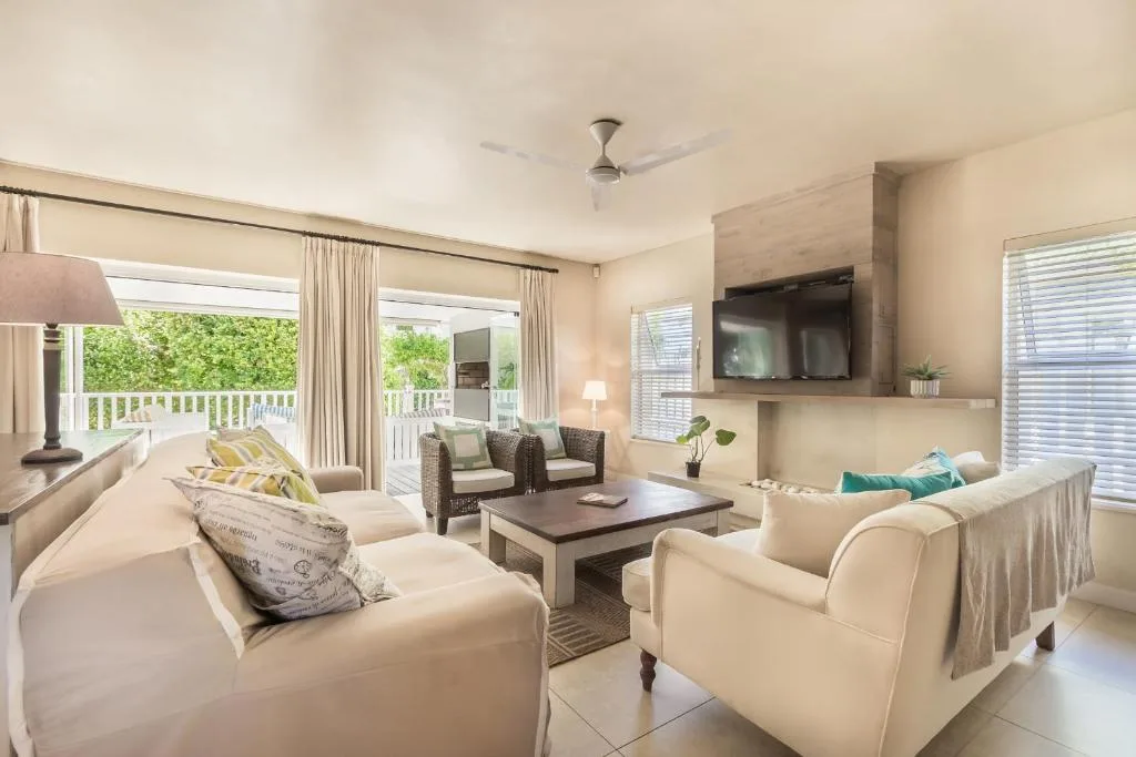 Spacious lounge with cream sofas, TV, and deck views
