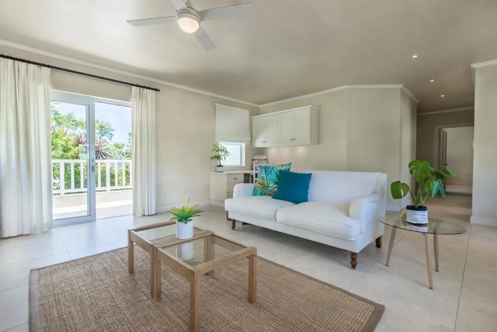 Bright open-plan lounge with white sofa, glass doors, and garden views