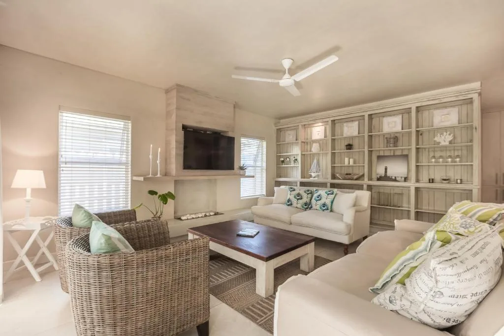 Spacious lounge with cream sofas, rattan chairs, and built-in shelving
