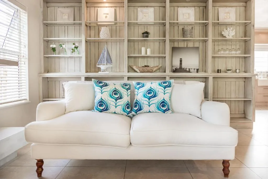 Cream sofa with blue patterned pillows and built-in shelving wall behind