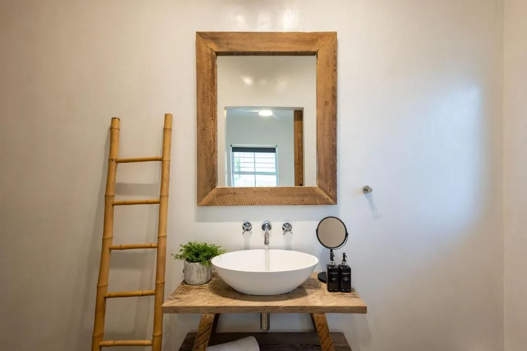 Modern bathroom vanity with round white vessel sink and wooden framed mirror