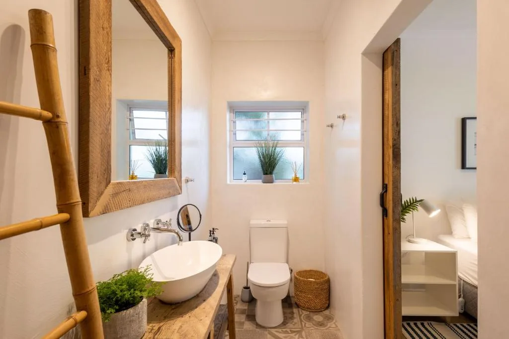 Bright bathroom with white basin sink, toilet, and decorative bamboo features