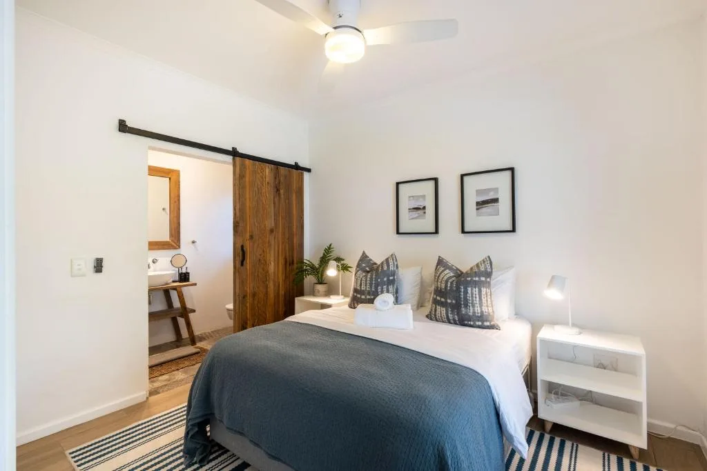 Bright bedroom with queen bed, sliding barn door, and ensuite bathroom entrance