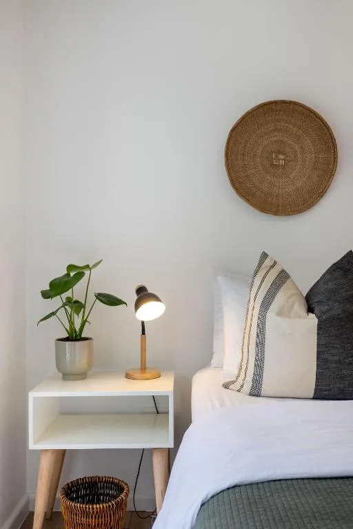 Cozy bedroom corner with bedside table, lamp, and decorative woven wall hanging