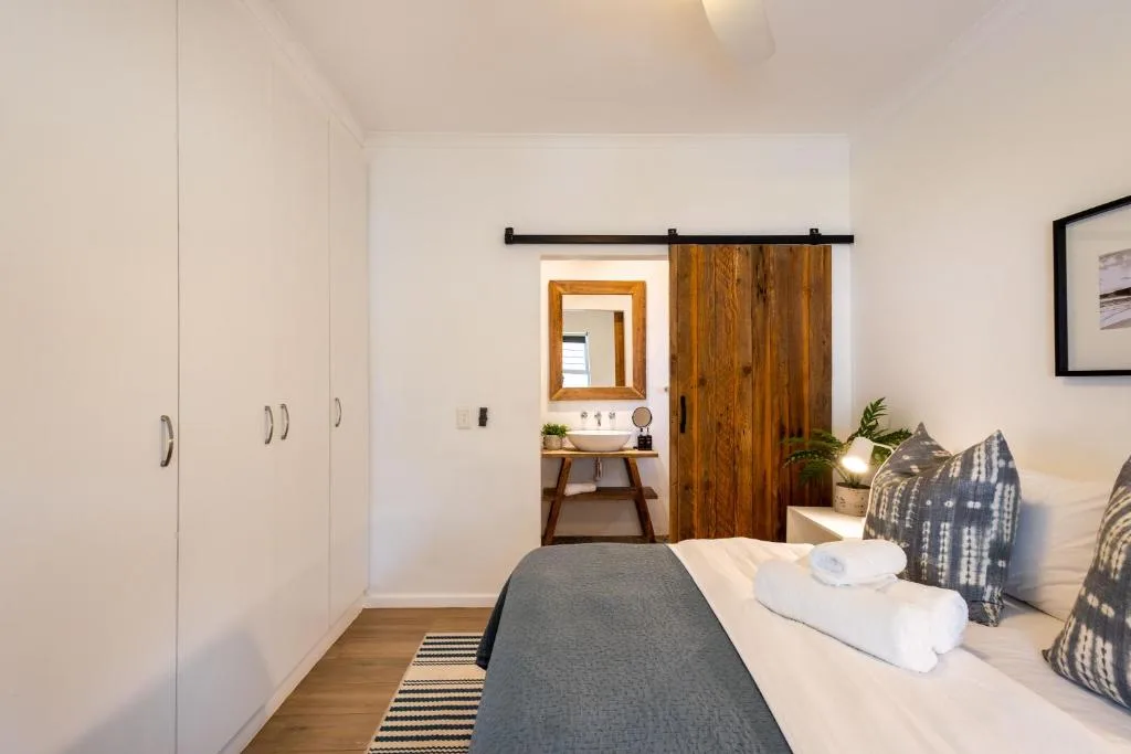 Bright bedroom with bed, wooden barn door, and ensuite bathroom visible