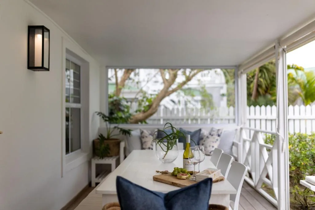Covered deck with dining table, seating, plants, and garden views