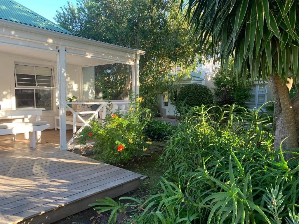 Wooden deck with white railings and lush garden surroundings at sunset