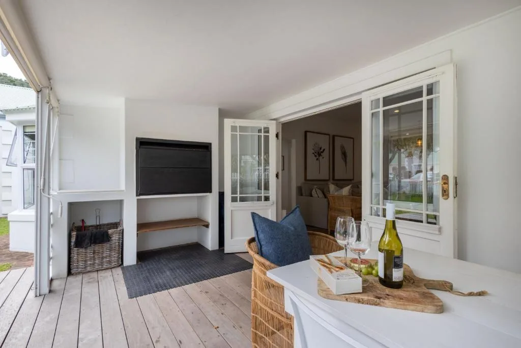 Covered deck with wicker furniture, wine bottle, and bedroom view beyond