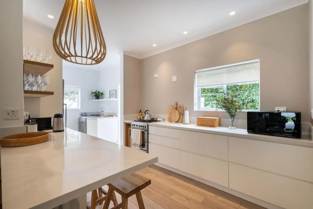 Modern kitchen with white cabinetry, stove, and pendant lighting fixture