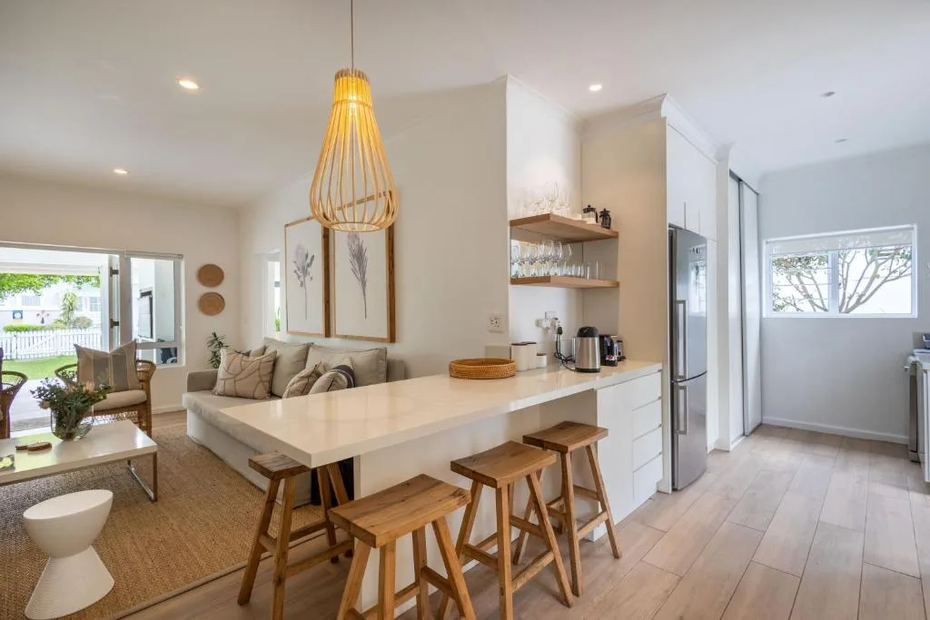 Modern kitchen with white countertops, wooden bar stools, and stainless steel appliances