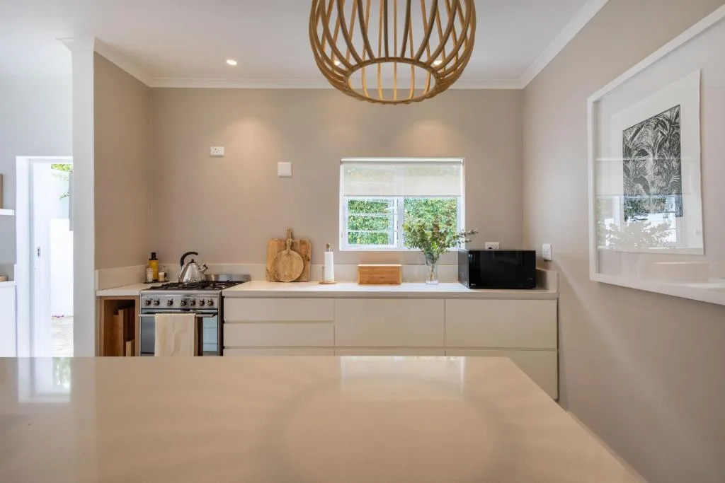 Modern kitchen with cream cabinetry, stove, and woven pendant light fixture