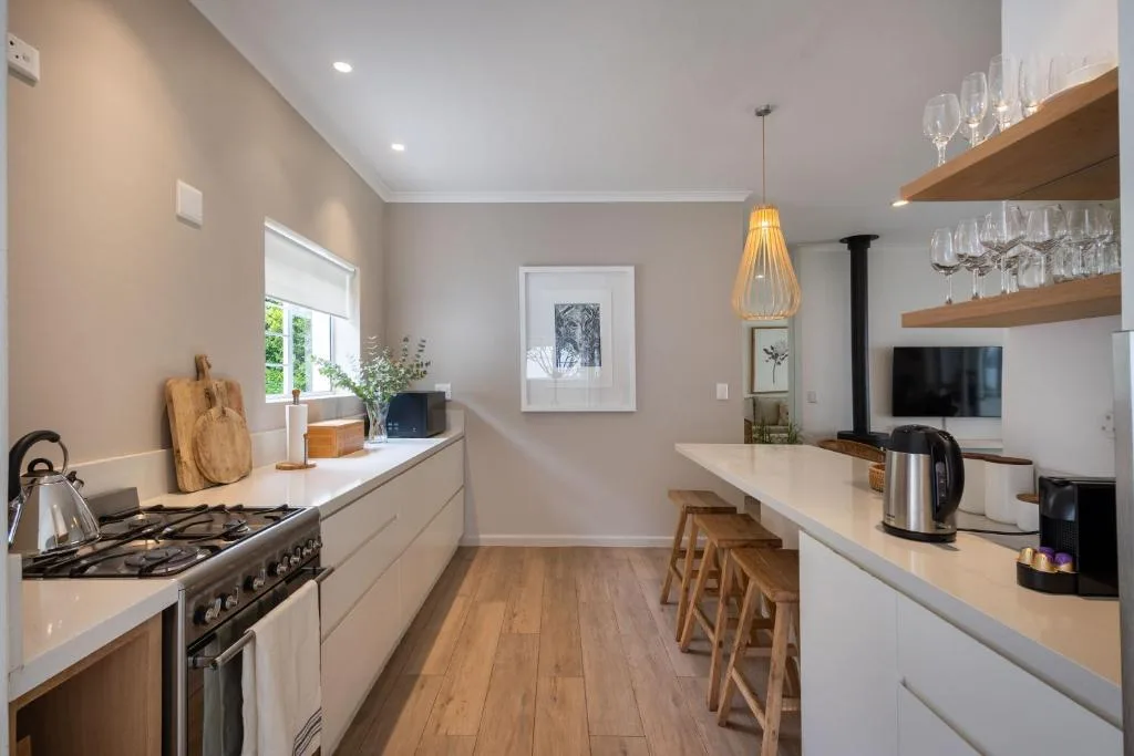Modern kitchen with gas stove, white cabinetry, wooden shelves, pendant lighting