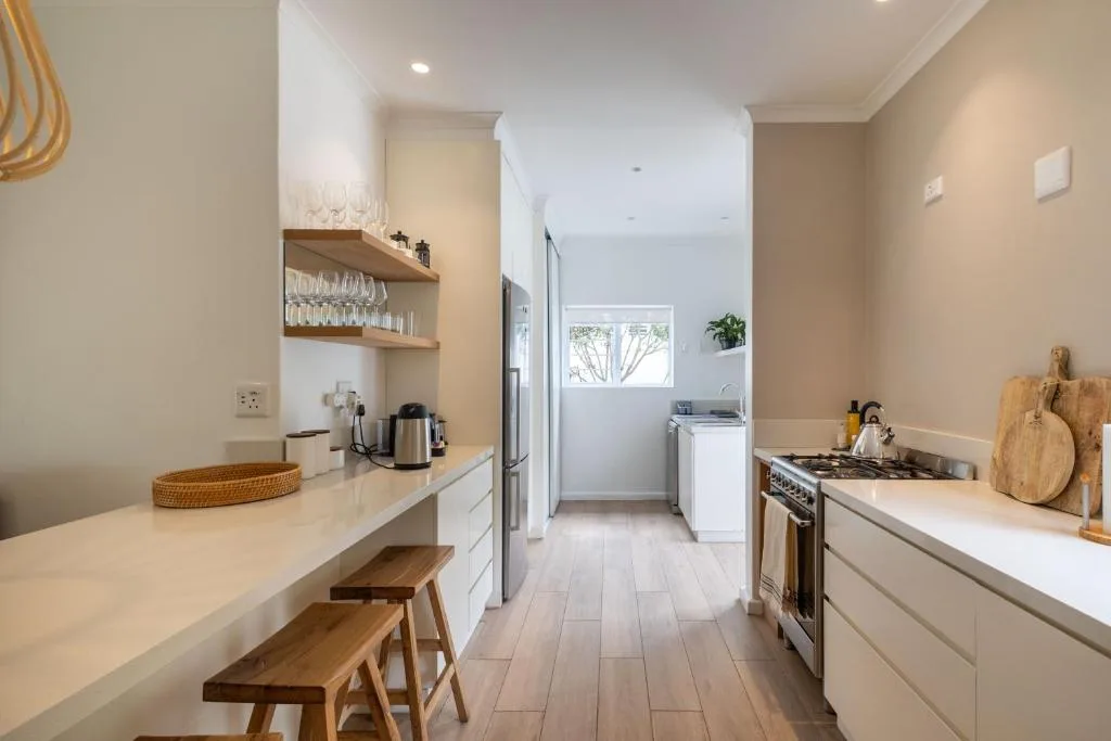Modern kitchen with white cabinetry, stainless steel appliances, and wooden seating