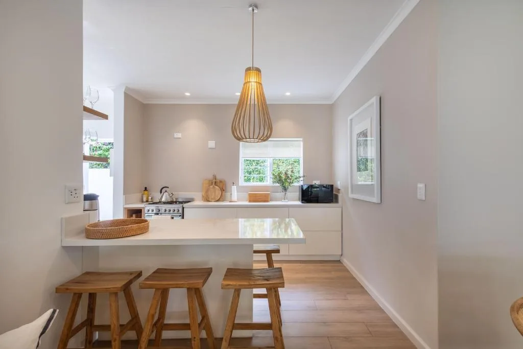 Modern kitchen with white counters, gas stove, and wooden bar seating