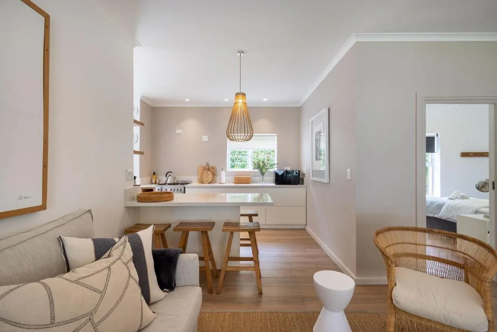 Modern open-plan kitchen with white cabinetry and wooden bar seating