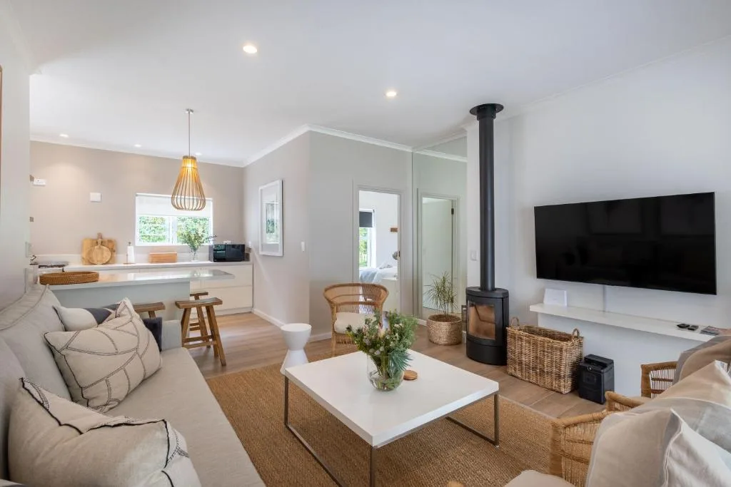 Modern lounge with sofa, TV, wood stove, and open-plan kitchen view