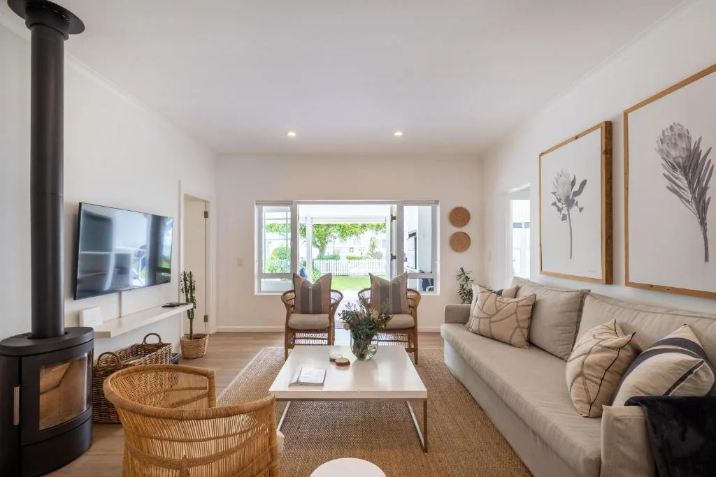 Modern lounge with fireplace, sofa, and garden views through glass doors