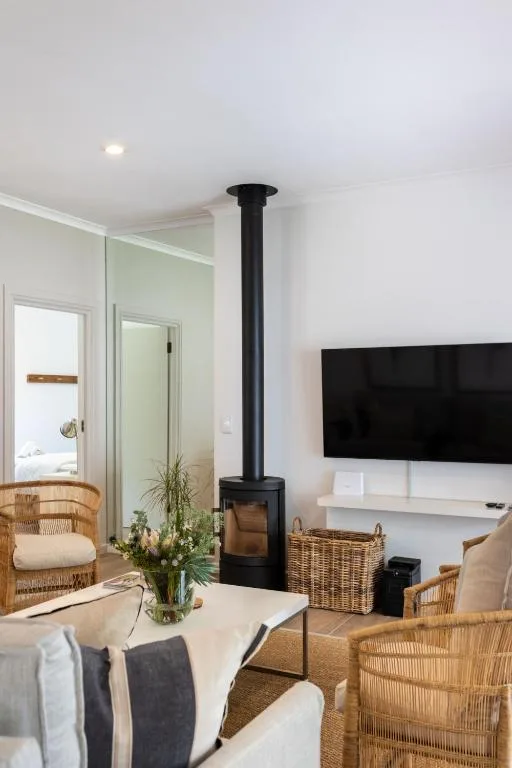 Modern lounge with fireplace, TV, wicker chairs, and garden view