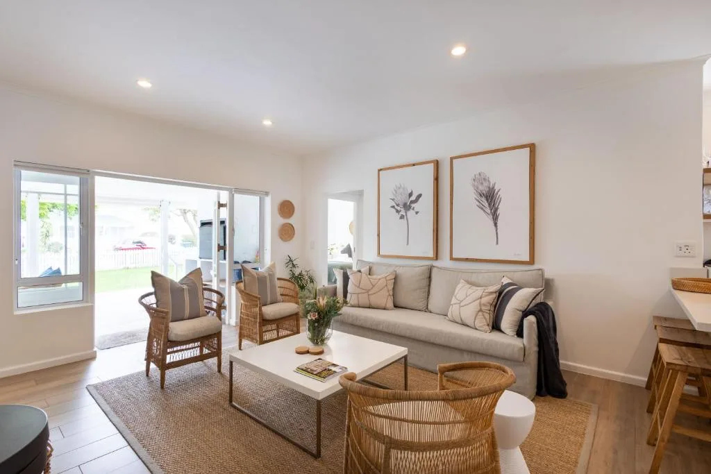 Bright living room with beige sofa, wicker chairs, and garden views through sliding doors