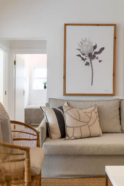 Comfortable beige sofa with decorative pillows and botanical artwork