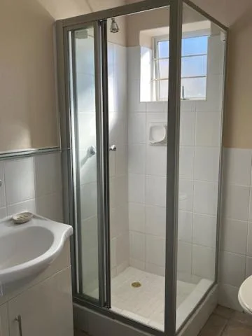 Modern shower enclosure with glass doors and white tile walls