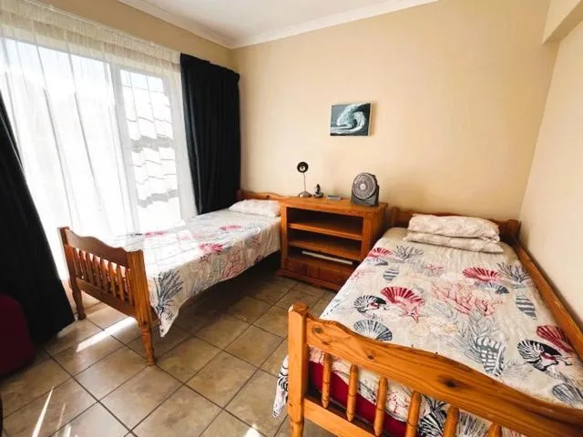 Twin bedroom with wooden beds, floral bedspreads, and bright windows