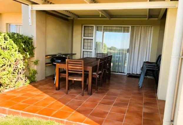 Covered patio with dining table, chairs, and garden views