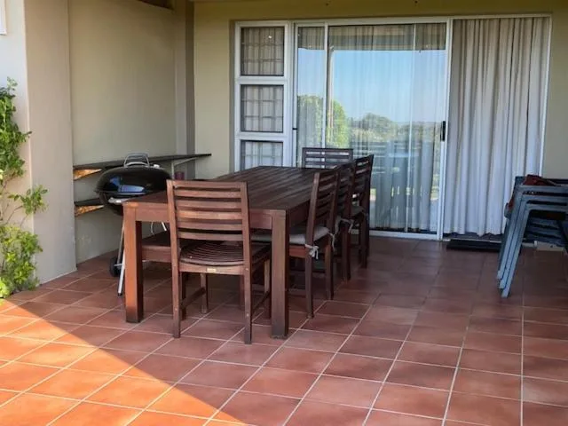 Outdoor patio with dining table, chairs, and braai grill area