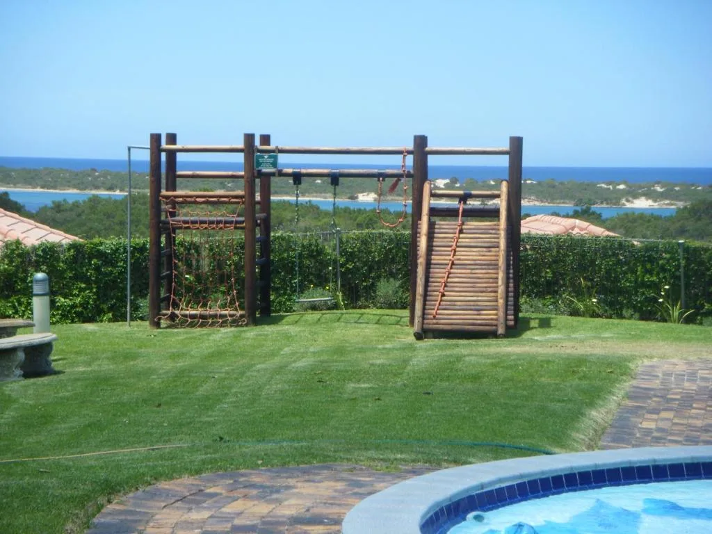 Wooden play structure on manicured lawn with ocean view beyond