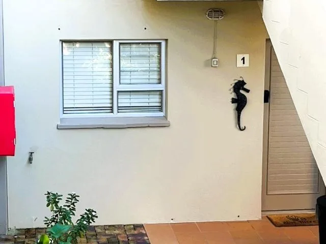 Cream-colored apartment facade with window, door, and decorative seahorse
