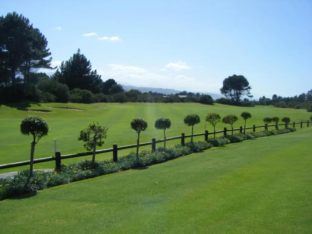 Manicured gardens with topiary trees and black fencing overlooking lush green lawns