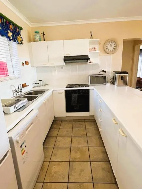 Compact kitchen with white cabinetry, black gas stove, and tiled flooring