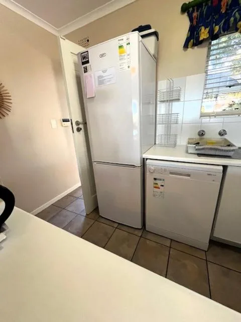 White refrigerator and dishwasher in compact kitchen with tile flooring