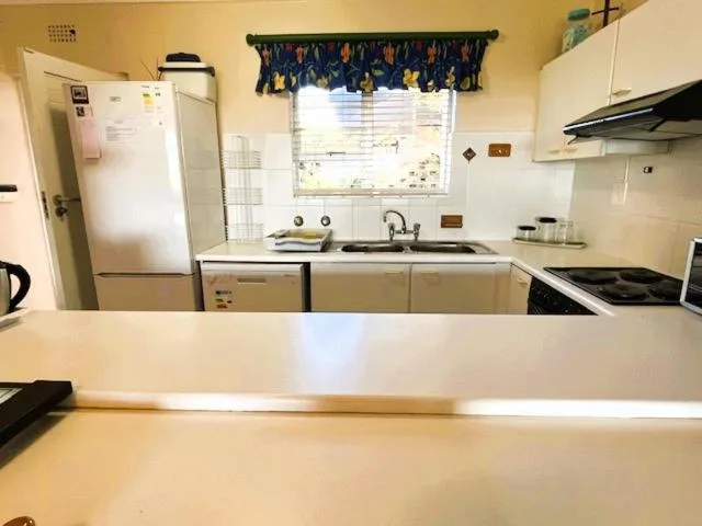 Compact kitchen with white appliances, sink, stove, and counter space