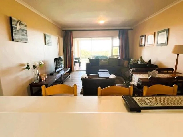 Spacious living room with dark sofa, dining chairs, and garden views through sliding doors