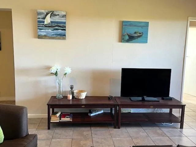 Living room with flat-screen TV, dark wooden entertainment unit, nautical artwork