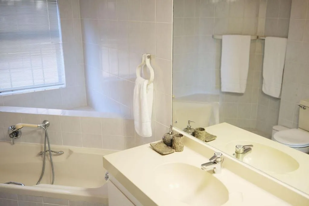 Clean bathroom with double vanity sink, bathtub, and white towels