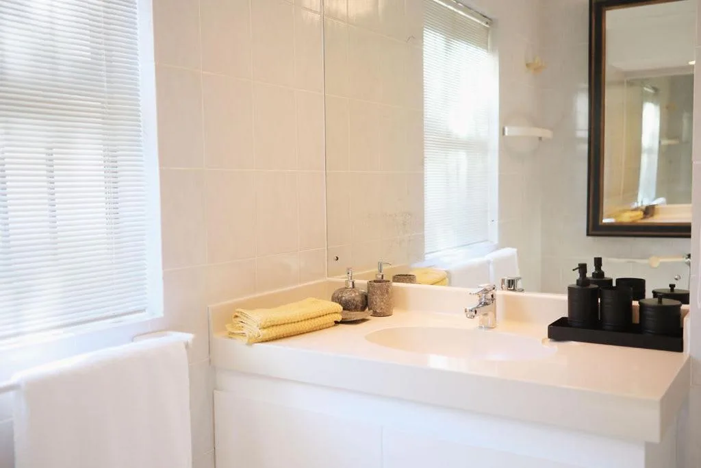 Modern bathroom with white countertop, mirror, shower enclosure, and amenities