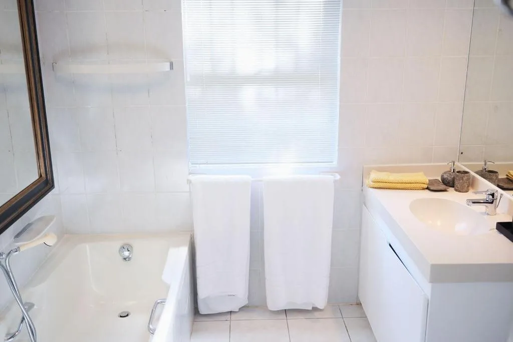 Clean white bathroom with bathtub, vanity sink, and bright window