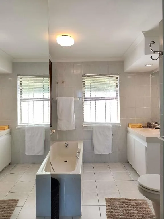 Bright bathroom with bathtub, dual sinks, and two windows with natural light