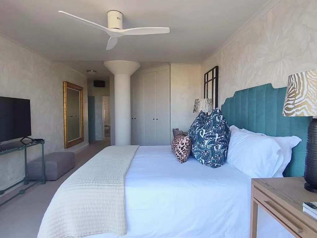 Modern bedroom with teal upholstered headboard and white bedding