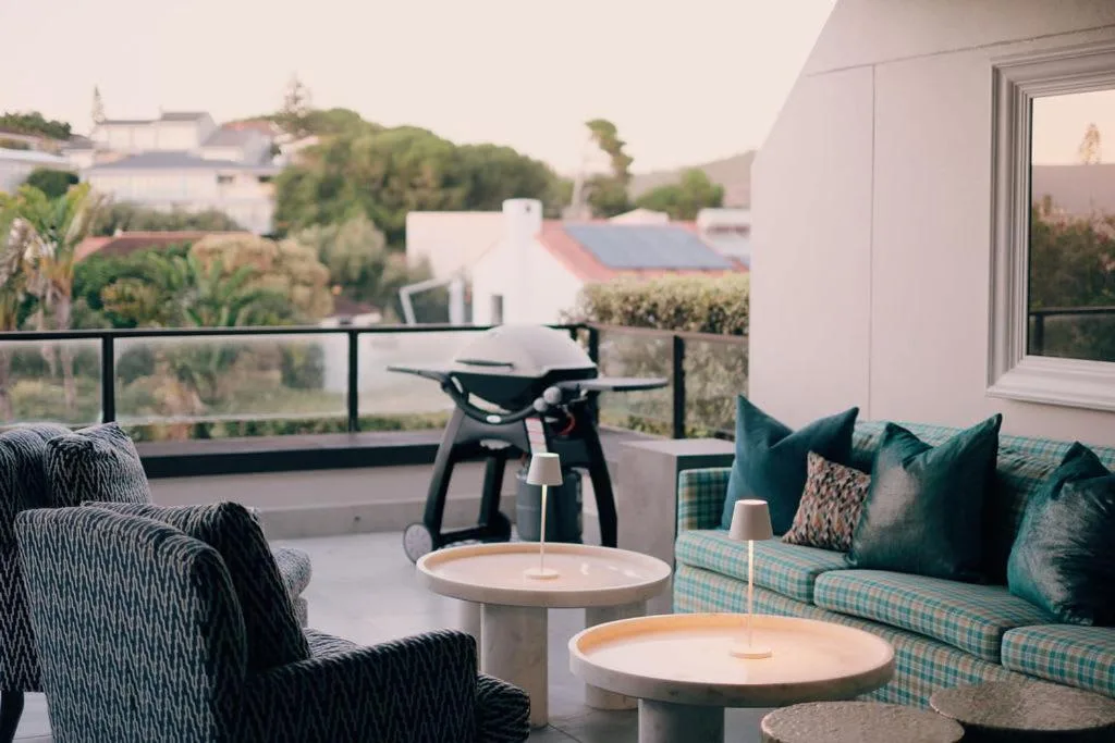 Outdoor balcony with seating, side tables, and neighborhood views