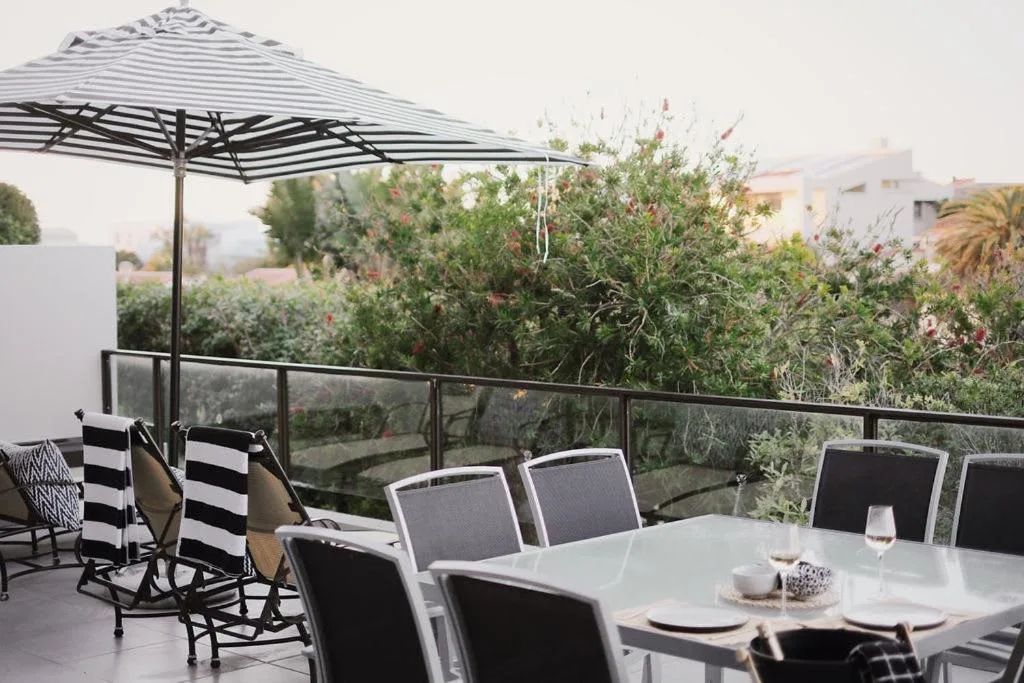 Outdoor dining area with striped umbrella and garden views on elevated deck