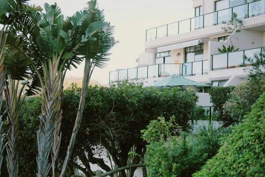 Modern white apartment building with balconies and lush tropical garden landscaping