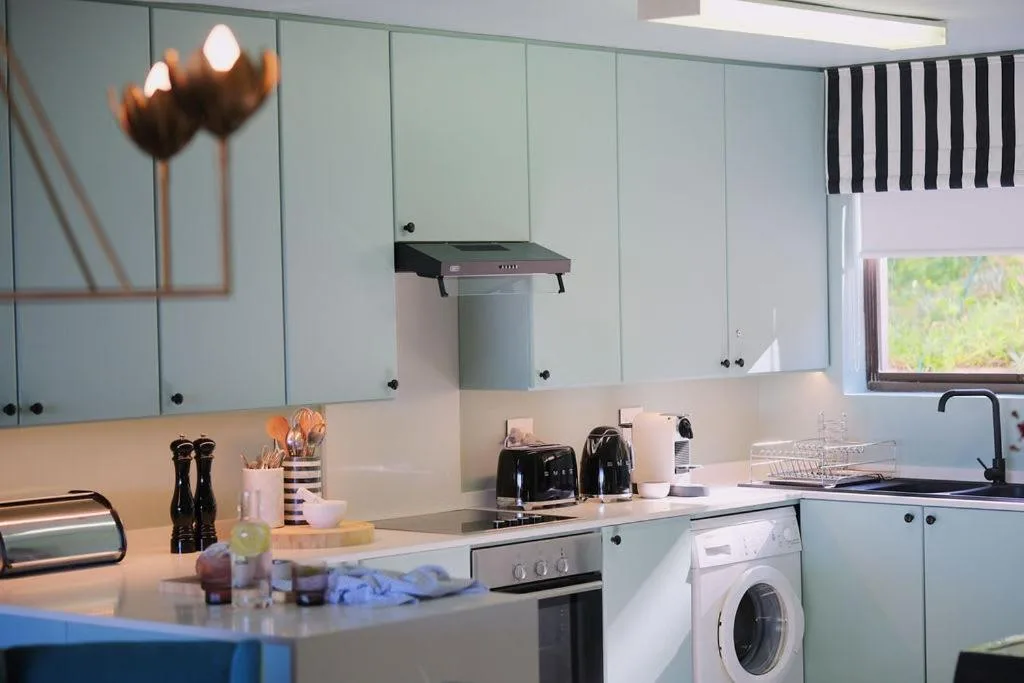 Modern kitchen with pale blue cabinetry, stainless steel appliances, and granite countertops