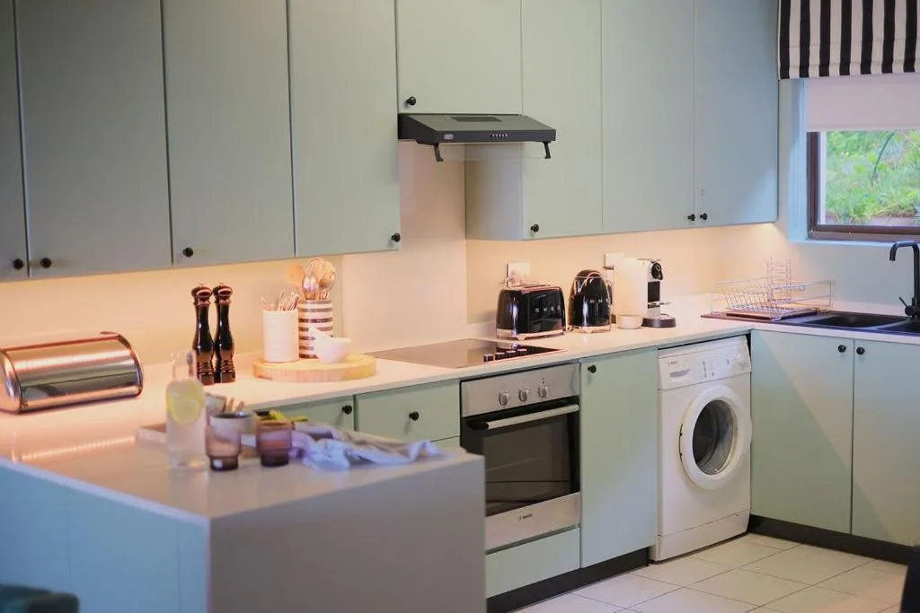 Modern kitchen with white cabinetry, stainless steel appliances, and stone countertops