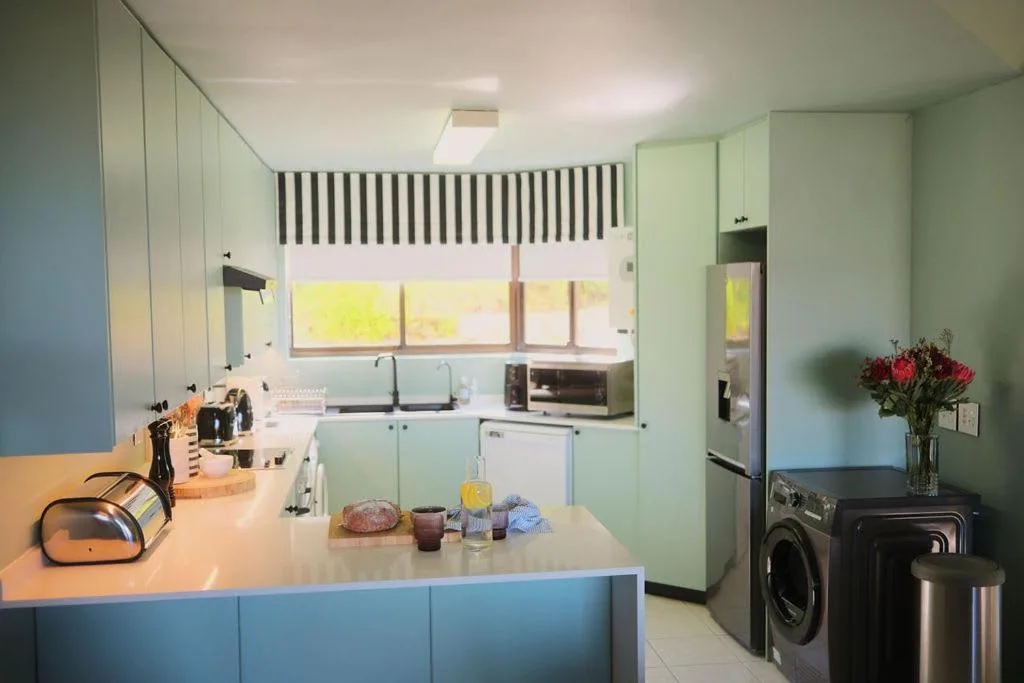 Modern kitchen with mint cabinetry, island counter, and stainless steel appliances