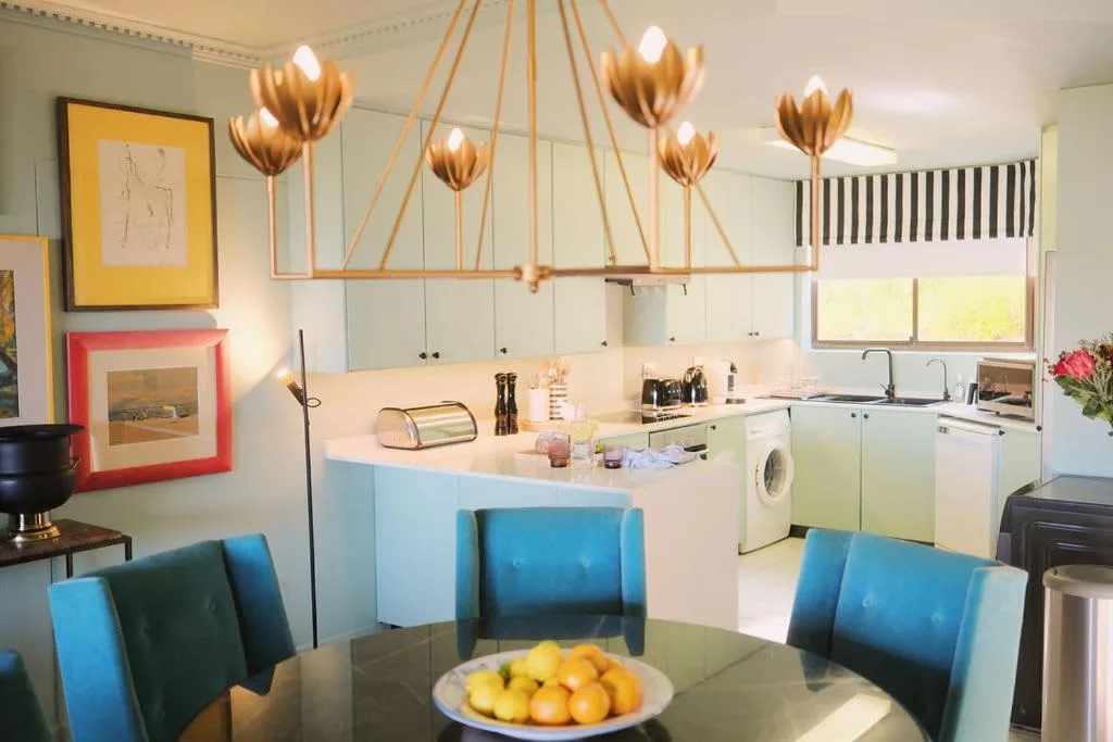 Modern kitchen with white cabinetry, gold pendant lights, and dining table